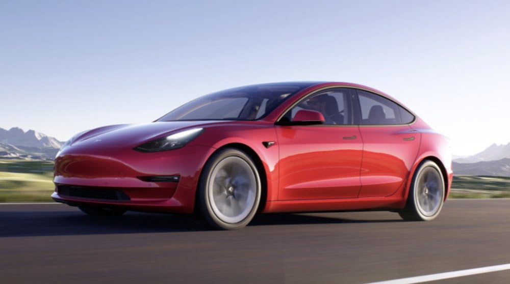 Teslas Model 3 in rot fährt über eine Straße.