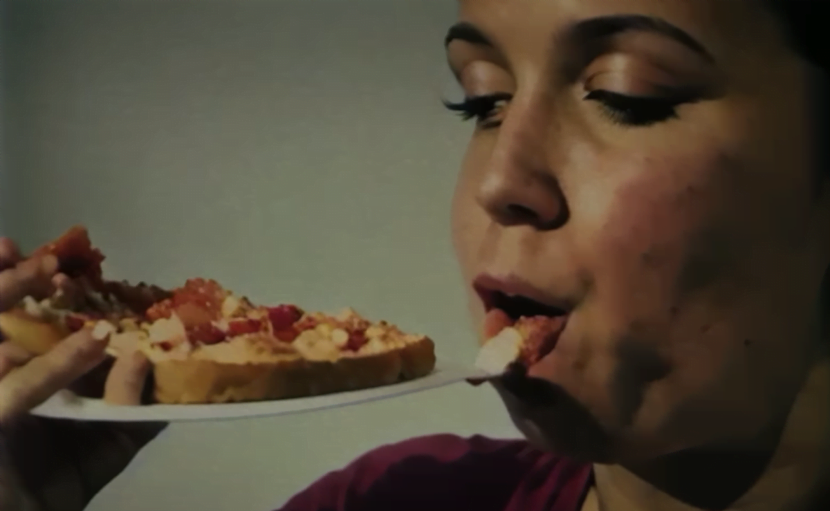 Eine Frau isst den Teller, auf dem eine Pizza liegt. Die Szene ist mit KI generiert.