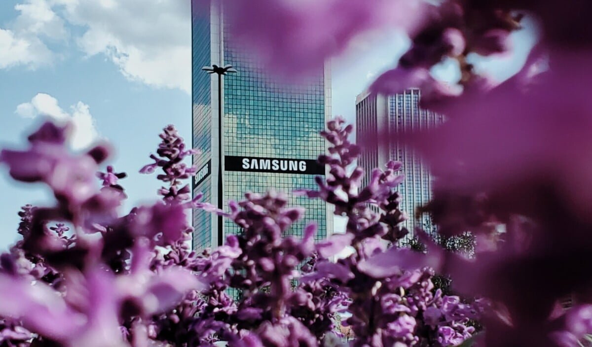 Das Samsung Logo an einem Firmengebäude, fotografiert durch einen Kirschblütenbaum.
